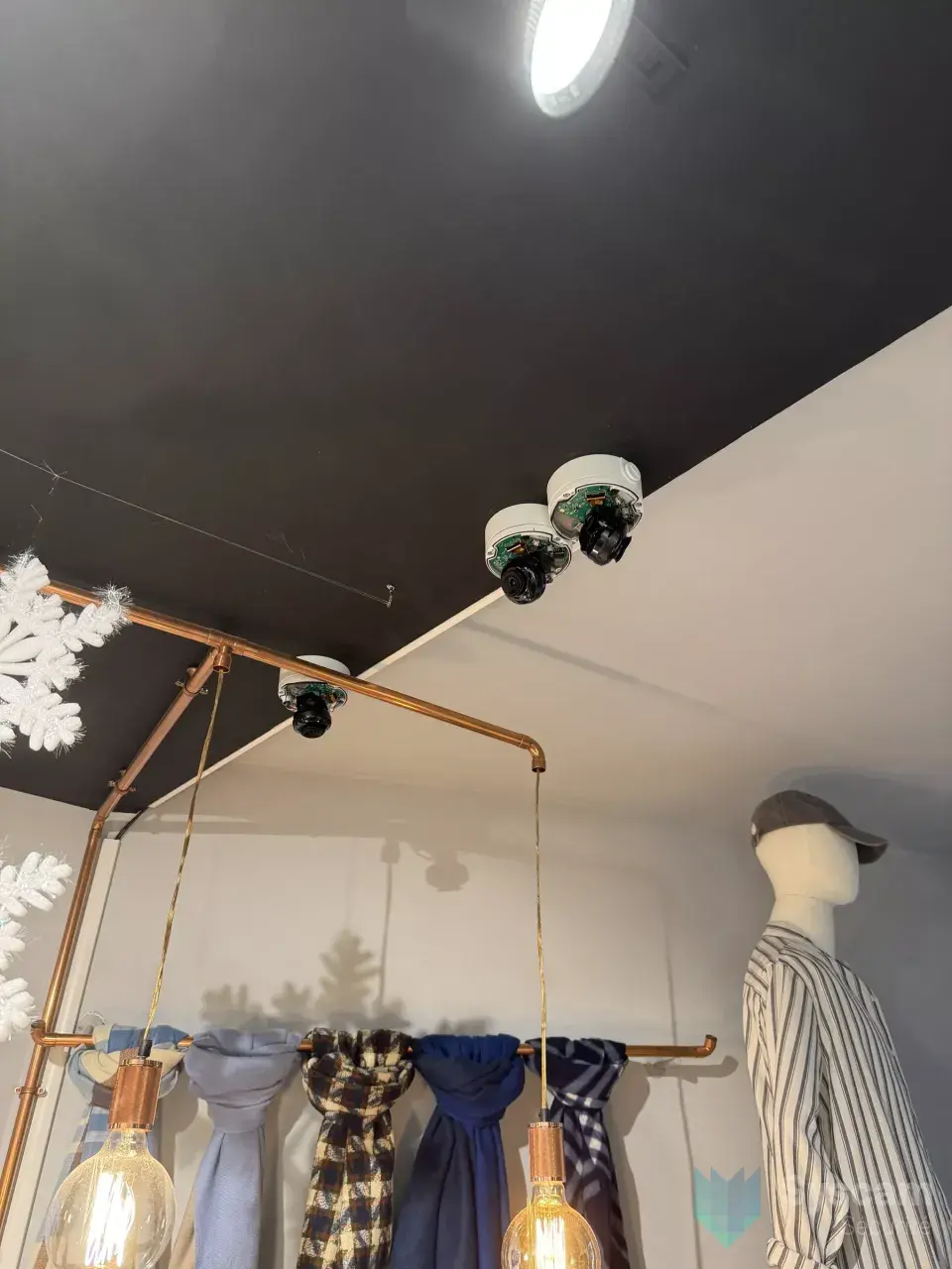 Pose des caméras dômes au plafond du magasin, capots ouverts pendant le raccordement au-dessus des portants d'écharpes