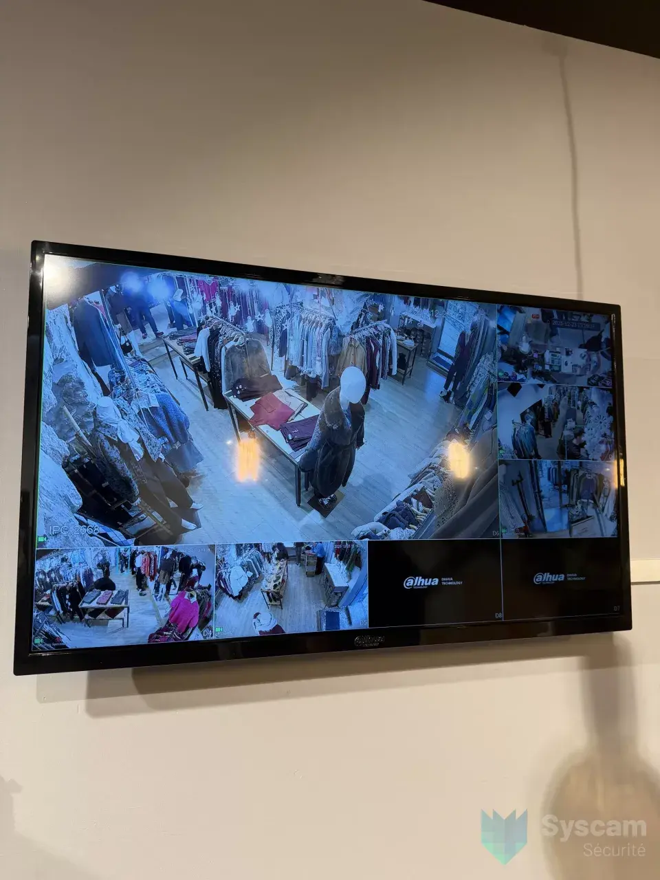 Moniteur de vidéosurveillance en gros plan : la surface de vente et les portants du magasin filmés en haute définition